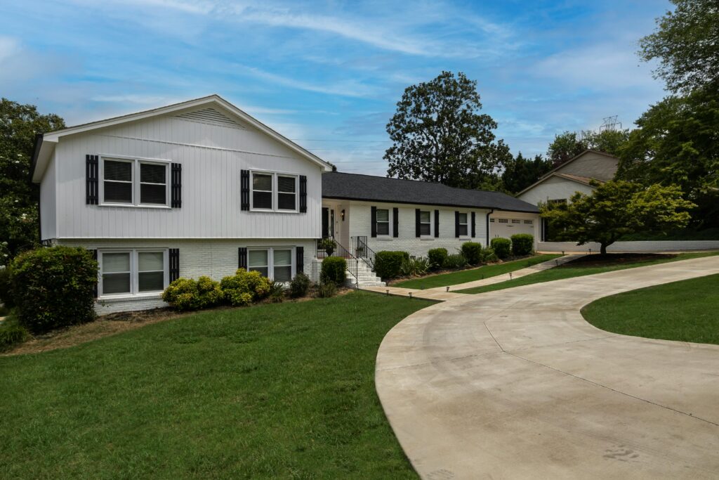 Modern suburban home with a large driveway and lush green lawn under a clear blue sky.
