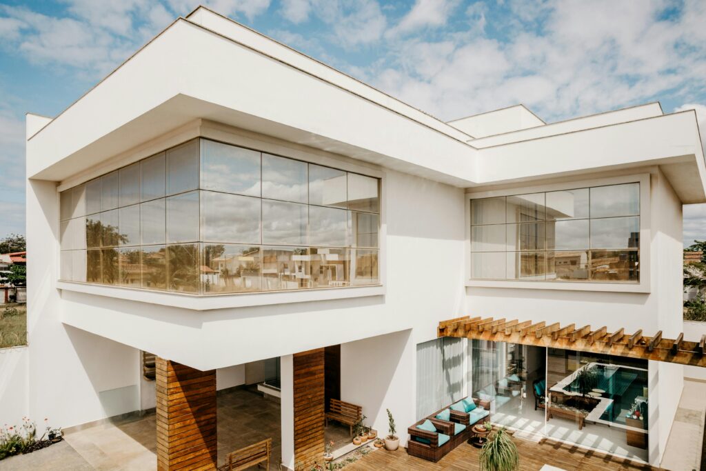 Exterior of contemporary cottage with large windows and stylish terrace against cloudy blue sky